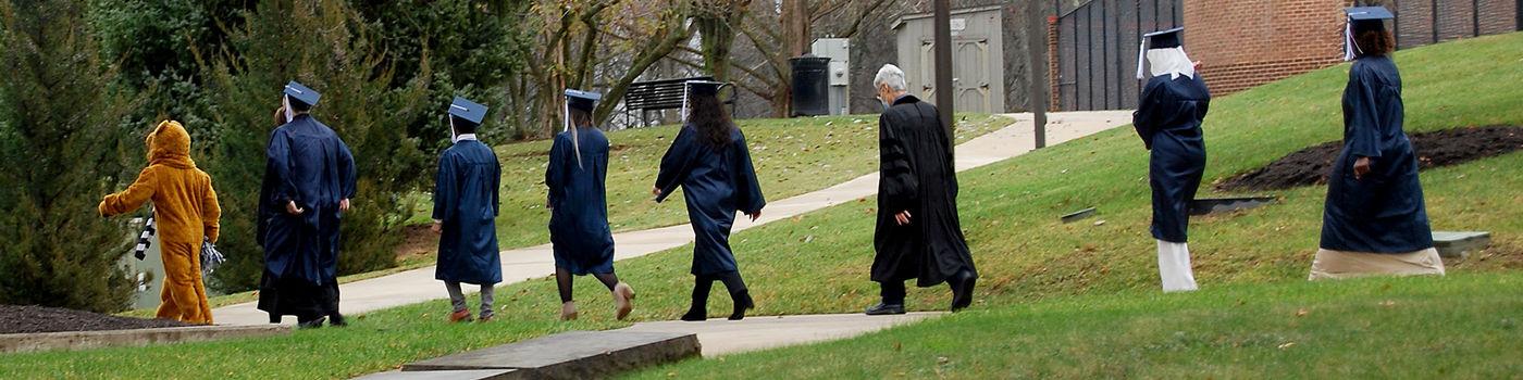 Students walking to commencement with Nittany Lion